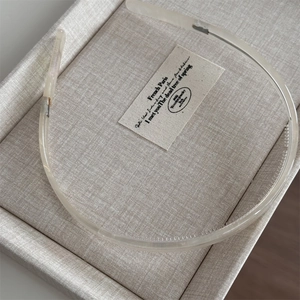 Detail of clear acetate headband with anti-slip inner teeth on beige linen tray