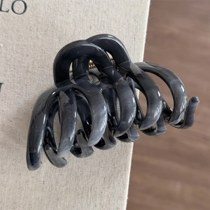 Macro detail of ink-wash marble hair claw clip with glossy finish on linen background