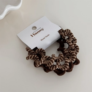 Dettaglio di elastici per capelli ondulati in toni terra con texture intrecciata a mano