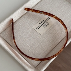 Close-up of tortoise shell headband with fine inner non-slip teeth on beige display tray