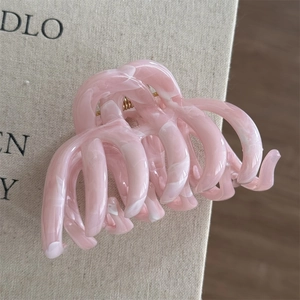 Macro detail of large pink marble resin hair claw clip with golden metal spring