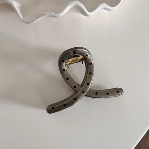 Detail of translucent grey hair claw clip with black polka dots and gold metal spring