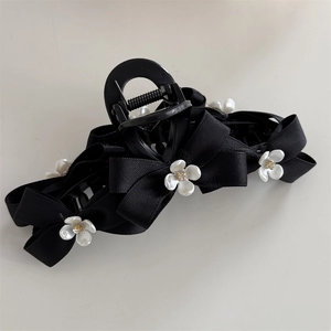 Detail of black satin bow hair claw clip with white rhinestone flower embellishments