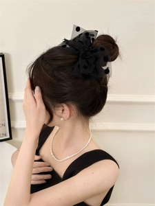 Close-up of a large black polka dot mesh bow hair clip on an elegant updo hairstyle