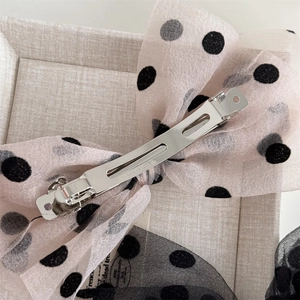 Detail of pink mesh polka dot bow hair clip with silver spring metal fastener