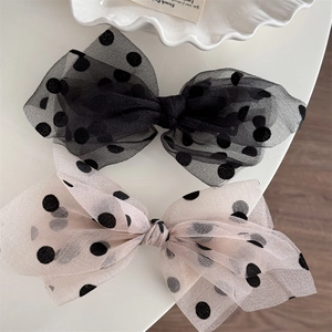 Close-up of elegant double-layered mesh polka dot bow hair clips in black and beige cream