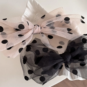 Detailed close-up of large mesh polka dot bow hair clips in pink and black colors