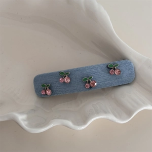 Nahaufnahme einer blauen Denim-Haarklammer mit vier Kirschmustern aus rosa Strass