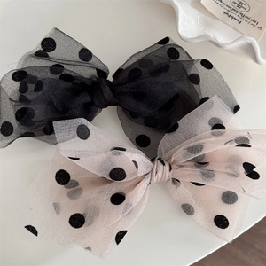 Close-up of elegant mesh polka dot bow hair clips in black and apricot colors