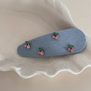 Detailaufnahme der Strass-Kirsch-Denim-Haarklammer mit rosa Kristallen und blauem Stoff
