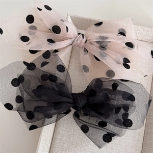 Detail of elegant mesh polka dot bow hair clips in pink and black on display