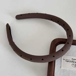Close-up of wide-brimmed brown fabric headband with black polka dots in French style