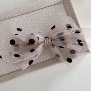 Close-up of pink mesh bow hair clip with black polka dots and spring metal fastening