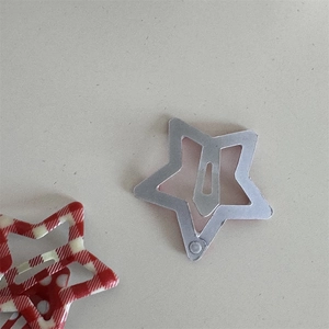 Close-up of red plaid and silver star-shaped snap hair clips for women and girls