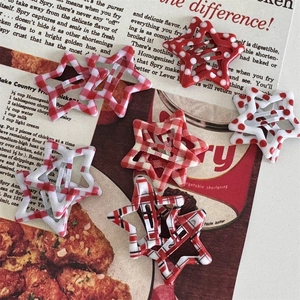 Close-up of star-shaped hair clips featuring red plaid, polka dots, and stripes