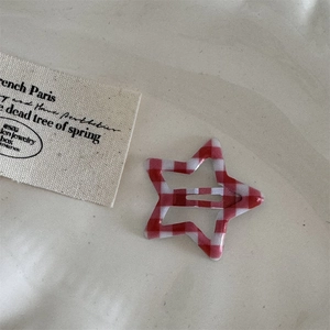 Detail view of a star-shaped BB hair clip with a red and white gingham plaid pattern