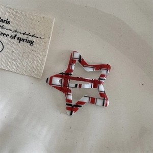 Detailed view of red and black plaid star-shaped hair clip on a neutral background