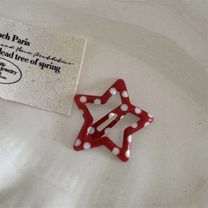 Macro shot of a red star-shaped hair clip with white polka dots on a textured background