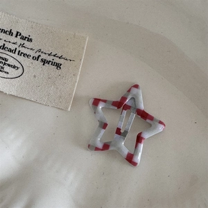 Detail of star-shaped red gingham hair clip with glossy finish and metal structure