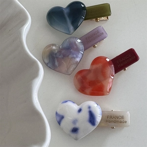 Detailed macro view of acetate heart hair clips with marble patterns and gold lettering