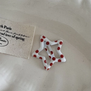 Detailed close-up of a star-shaped hair clip with red polka dots and silver metal core