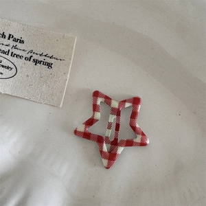 Detailed view of a red gingham star hair clip with fabric texture and metal structure