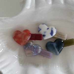 Macro detail of heart-shaped acetate hair clips with France Handmade gold engraving