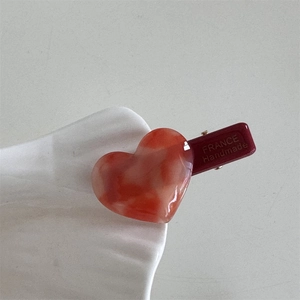 Detailed close-up of a red marble heart hair clip with FRANCE Handmade lettering