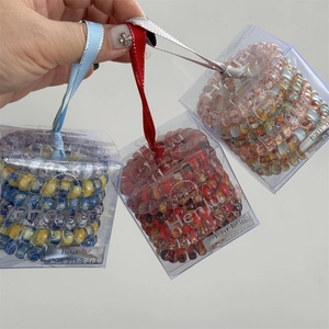 Hand holding floral spiral hair bands in clear gift boxes with satin ribbon handles