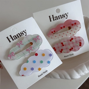 Detail of cute wave cloud hair clips with polka dots and cherry prints on display card