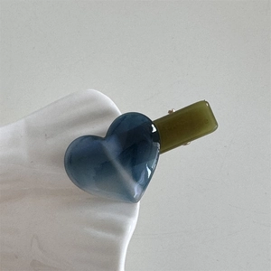 Close-up of marble pattern resin heart hair clip with olive green acetate base
