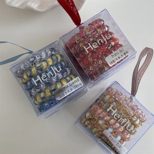 Detailed view of floral spiral hair ties in transparent gift boxes with silk ribbon handles