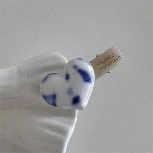 Detail view of heart-shaped blue marble acetate hair clip with France Handmade logo
