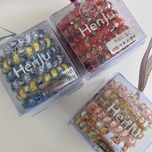 Three transparent boxes showcasing floral spiral telephone wire hair bands on white desk