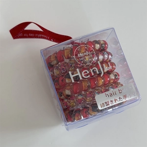 Detail of floral spiral hair ties in a transparent gift box with red ribbon decoration