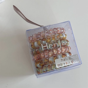 Detailed close-up of colorful floral spiral telephone wire hair ties in a transparent box