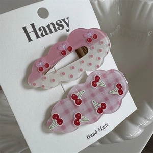 Detail of pink cloud-shaped hair clips with cherry motifs and bow on white card