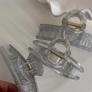 Close-up of glitter hair clips with silver acrylic texture and golden metal spring