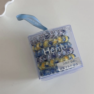 Floral spiral hair ties set in a clear gift box with decorative blue satin ribbon