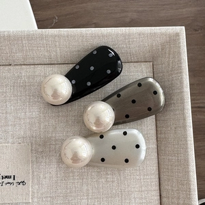 Polka dot pearl hair clips in black, grey, and beige shown on a fabric display tray