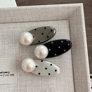Close-up of vintage polka dot pearl hair clips in grey, black and cream on display