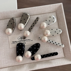 Polka dot hair clips with large white pearls in French retro style on a beige tray