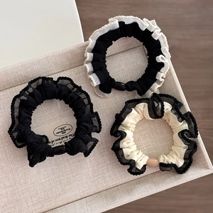 Detailed view of three lace scrunchies with pearl beads on a beige jewelry display tray