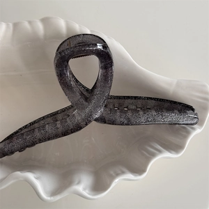 Close-up of a charcoal grey translucent hair claw clip with silver glitter and curved design
