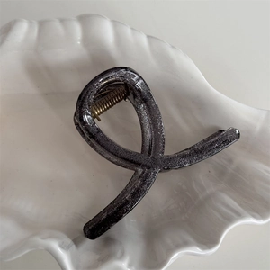Detail of elegant black translucent hair claw with silver glitter and gold metal spring
