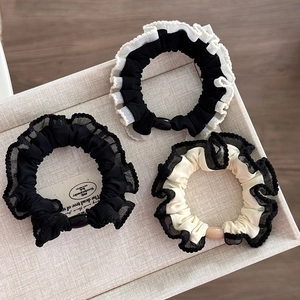 Detailed macro view of three lace elastic scrunchies on a wooden textured jewelry tray