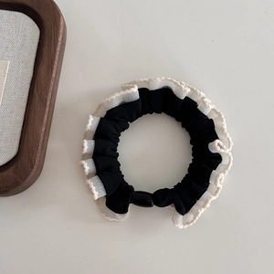 Detail of black and white ruffled scrunchie with polka dot edges and oval bead accent