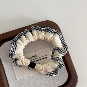 Detail of vintage beige scrunchie with classic black and white plaid lace trim edge