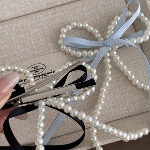 Barrettes à cheveux élégantes en perles avec rubans bleu clair et noirs sur beige