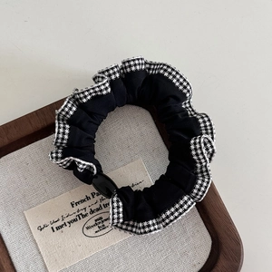 Detailed view of black scrunchie with houndstooth lace trim and a glossy buckle detail